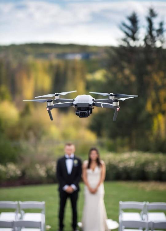 Little flying drone in a wedding flying over the white chrs with de groom and the bride on the defo